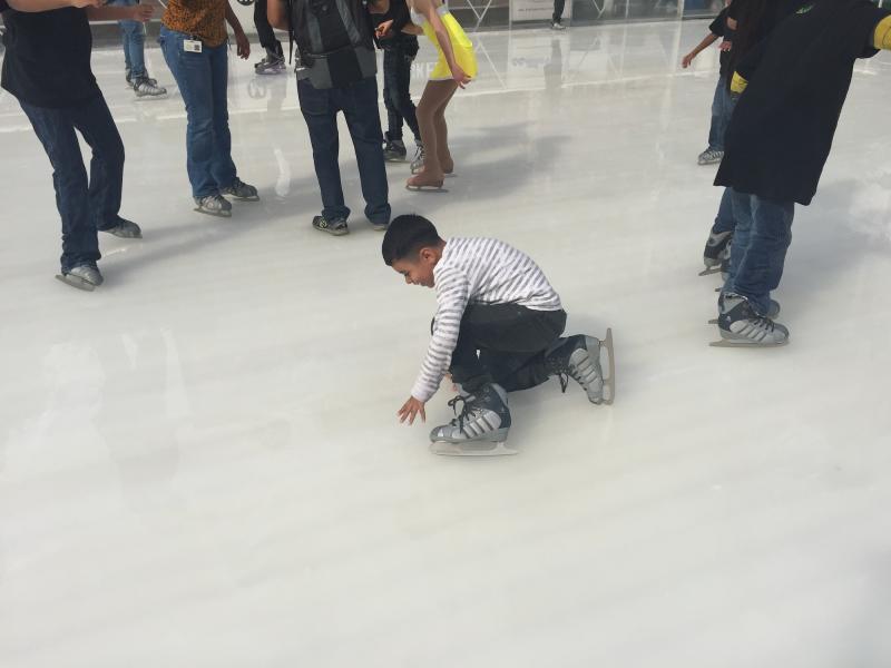 A young skater takes a tumble on the rink.