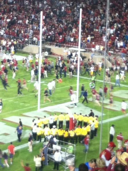 Security surrounds the goalpost as fans storm the field.