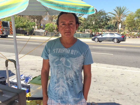 Vendor Oscar Rogel stands under an umbrella. (Scott Cook / Annenberg Media)