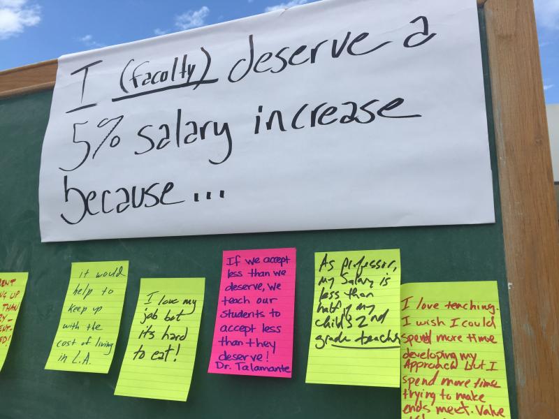 Faculty members post notes on a chalkboard explaining why they need a raise.