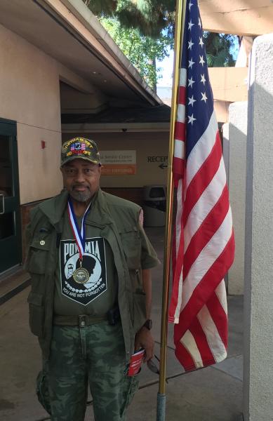 Vietnam Veteran Army Specialist Al C. Strange stands next to the American flag at the Pasadena Senior Center's annual Veterans' Day Luncheon on Nov. 11, 2015. (Stephanie Haney/Annenberg Media)